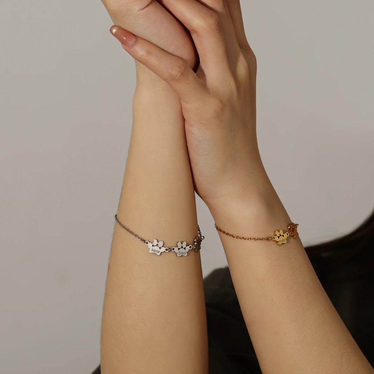 Silver and gold paw name bracelets worn on two wrists