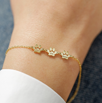 Three small engraved gold paws worn on the wrist