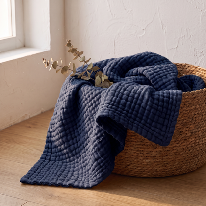 Navy gauze blanket folded in a woven basket