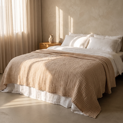 Sand gauze blanket over a made double bed with white linen