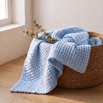 Sky gauze blanket folded in a woven basket