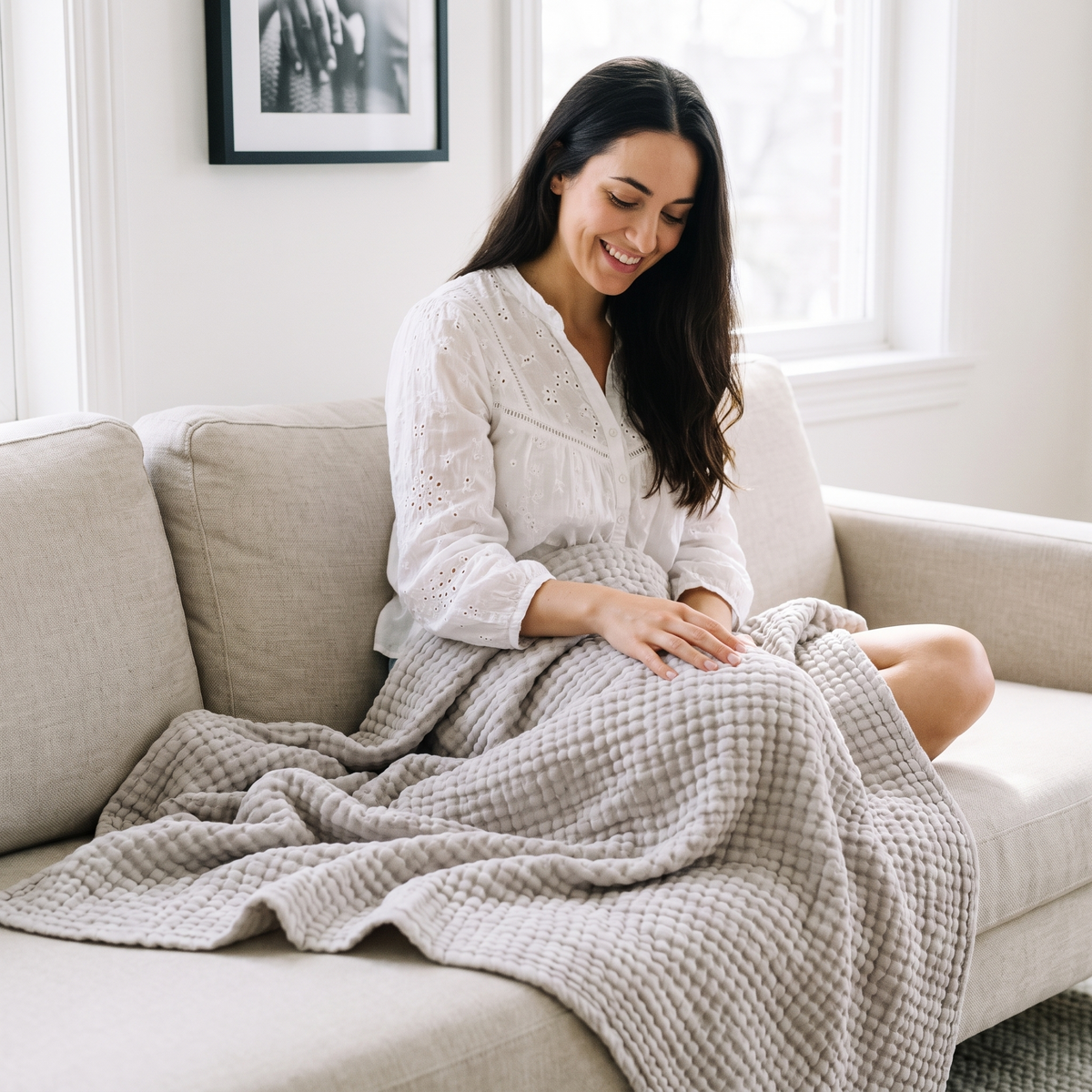 Woman on a sofa with a stone grey gauze blanket over her lap