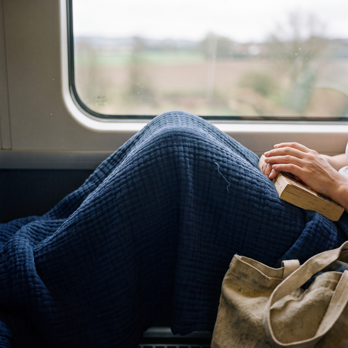 Navy gauze blanket over a passenger's knees on a train