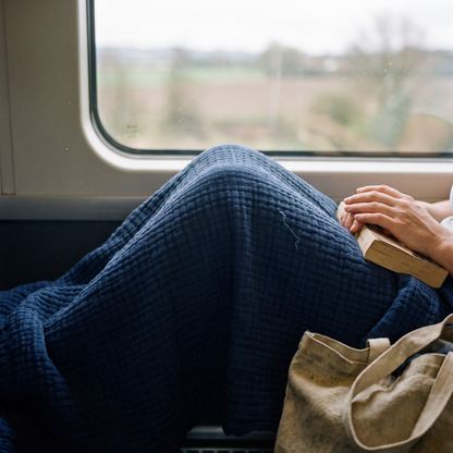 Navy gauze blanket over a passenger's knees on a train