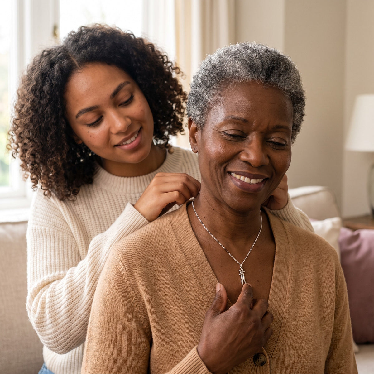 Daughter fastening the silver Hug Necklace on her mum at home