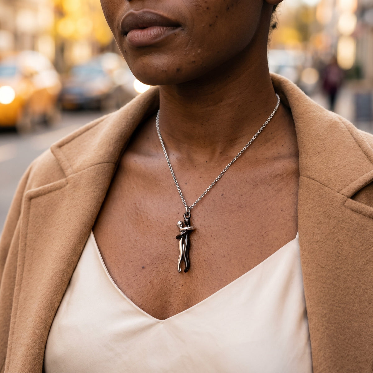 Hug Necklace in black and silver worn with a camel coat