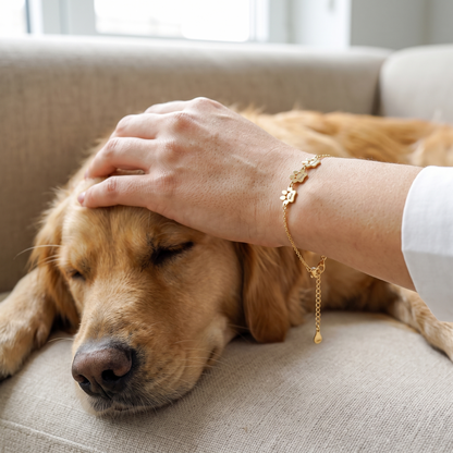 Gold paw name bracelet worn while stroking a sleeping golden retriever