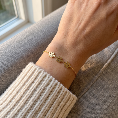 Gold paw name bracelet with three small engraved paws worn on the wrist