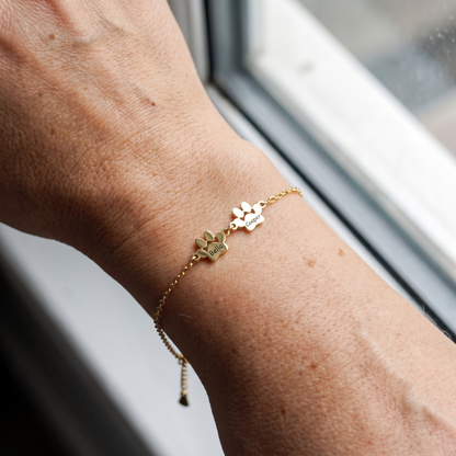 Two small engraved gold paws, Bella and Cooper, on the wrist